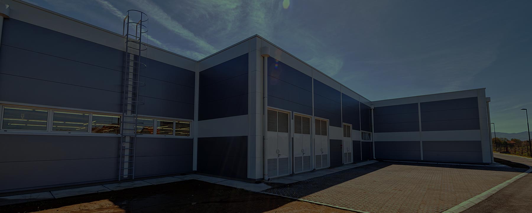 a low warehouse building with roll-up doors beside a paved yard